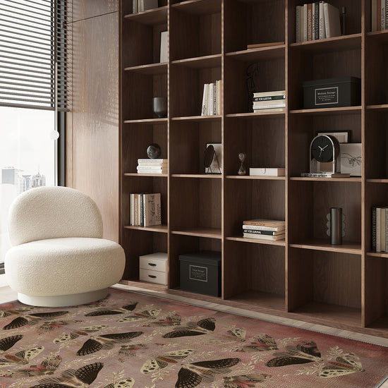 Modern living room with a large bookshelf, decorative rug, and armchair.