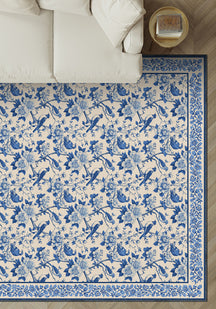 Blue and white floral and bird patterned rug on a wooden floor.